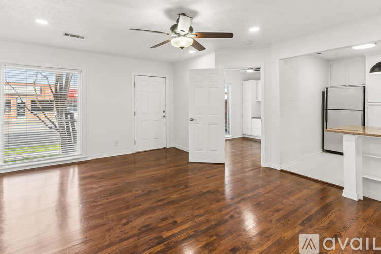A spacious room with wood flooring and a ceiling fan.