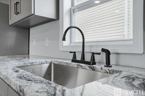 A kitchen sink with a marble countertop and a black faucet.