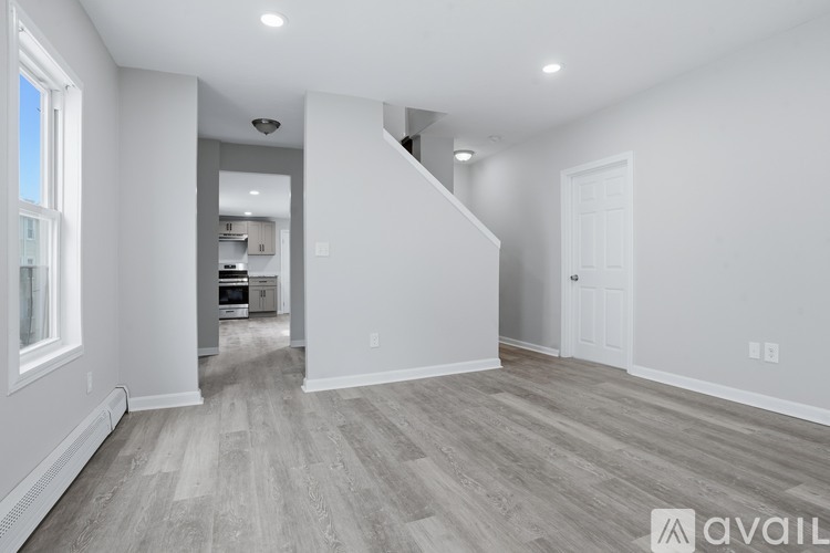 A spacious room with wooden flooring and white walls.