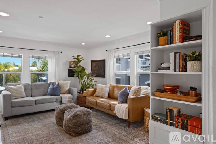 A living room with a grey sofa, a wooden coffee table, a beige armchair, and a bookshelf with various items.