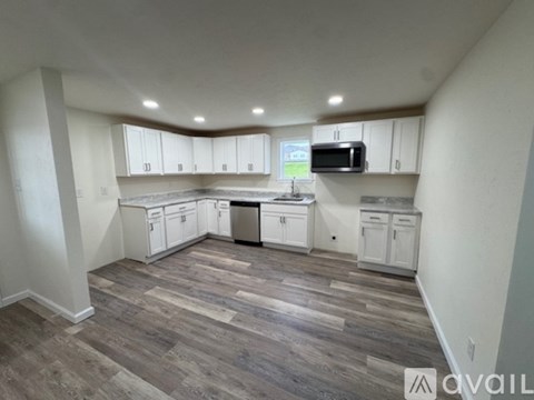 A kitchen with white cabinets and a wooden floor.