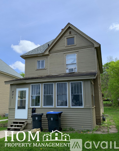 A two-story house with a white door and two windows on the ground floor and one window on the first floor.
