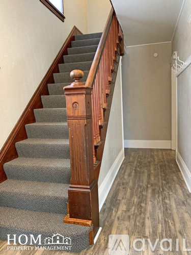 A staircase with a wooden handrail and grey carpeted steps.