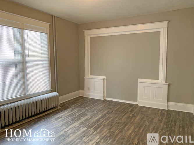 A room with a window, a radiator, and a wooden floor.