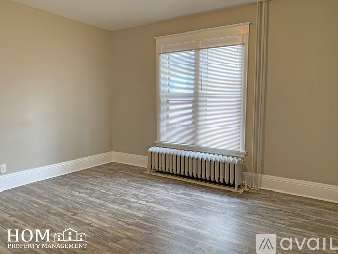 A room with a window and a radiator on the floor.