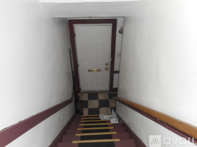 A hallway with a checkered floor leading to a door.