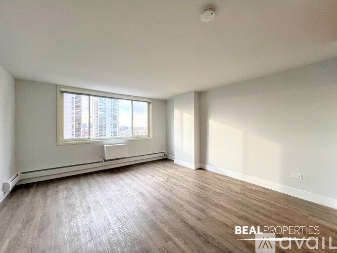 A spacious room with wooden flooring and a large window.