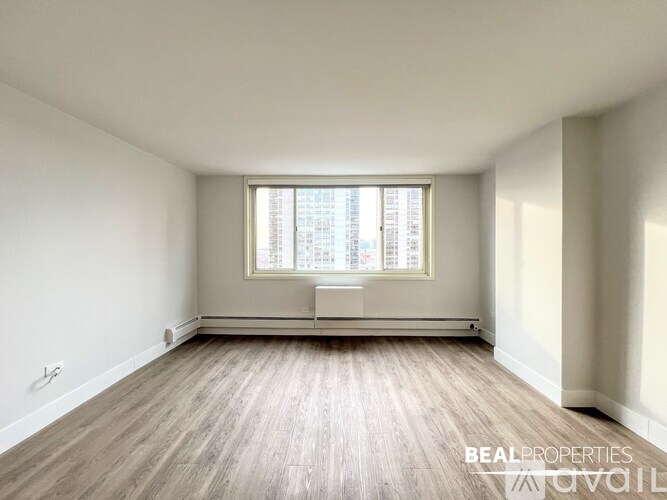 A spacious room with wooden flooring and a large window.