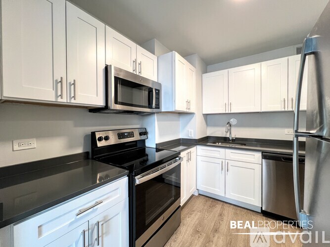 A kitchen with white cabinets and black appliances.