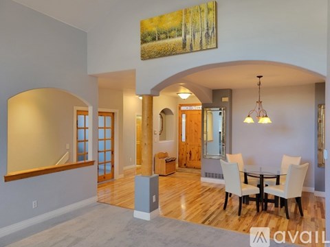 A dining room with a wooden floor and a large painting on the wall.