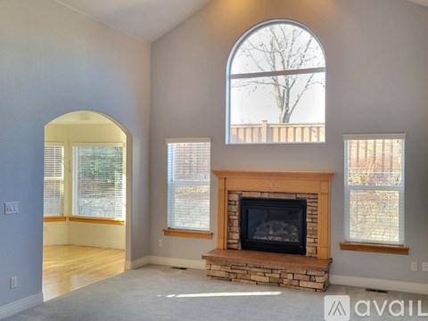 A living room with a fireplace and a large arched window.