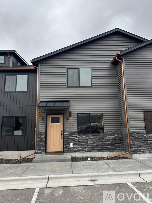 A grey house with a brown door and windows.