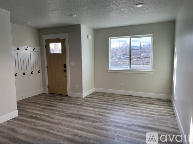A room with a wooden door and a window showing a view of a snowy landscape.