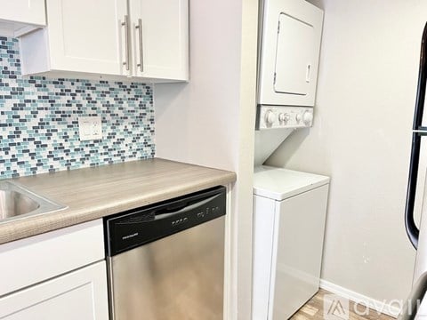 A white dishwasher is next to a white dryer in a kitchen.