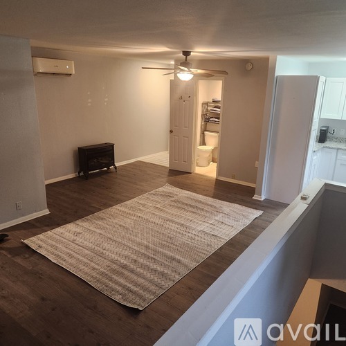 A room with a rug on the floor and a ceiling fan.
