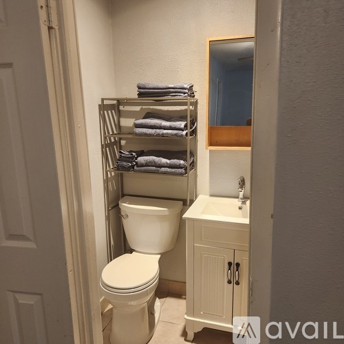 A white toilet sits next to a towel rack in a bathroom.