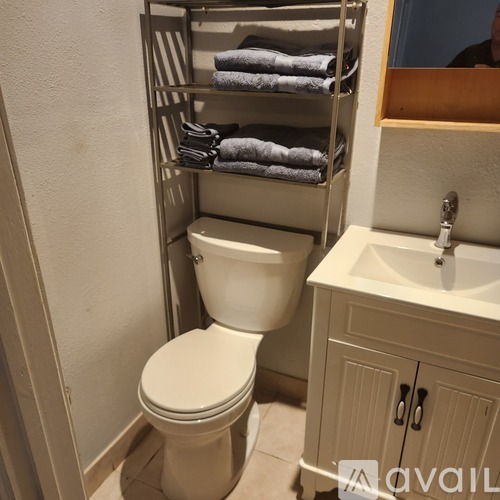 A white toilet sits under a towel rack in a bathroom.