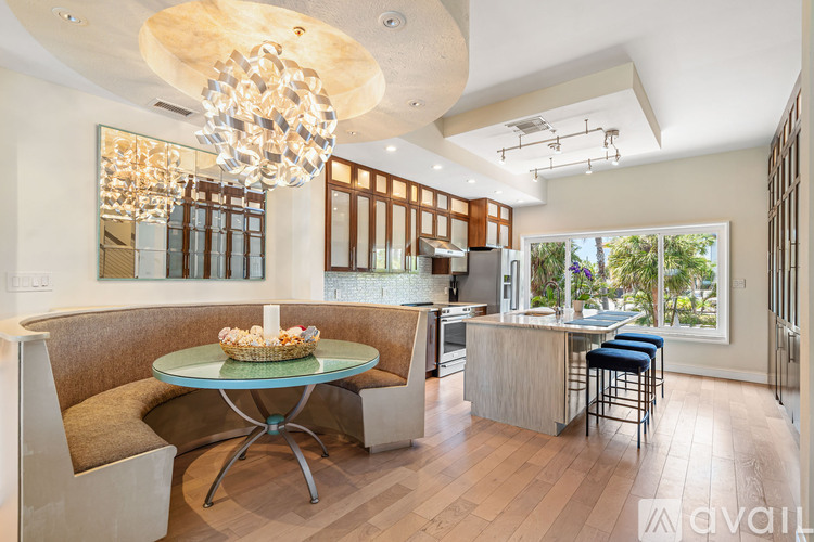 A modern dining room with a round glass table and a chandelier.