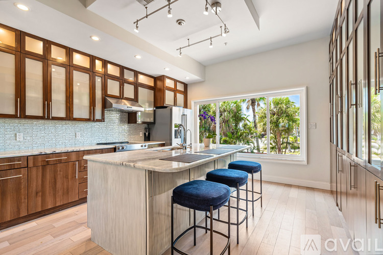 A kitchen with wooden cabinets and a large island with blue stools.