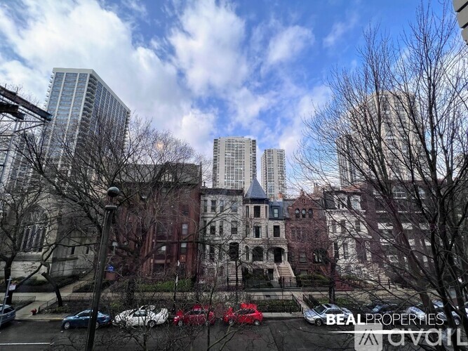 A large, historic-looking building is surrounded by modern buildings and bare trees.