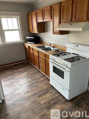 A kitchen with a white gas stove and wooden cabinets.