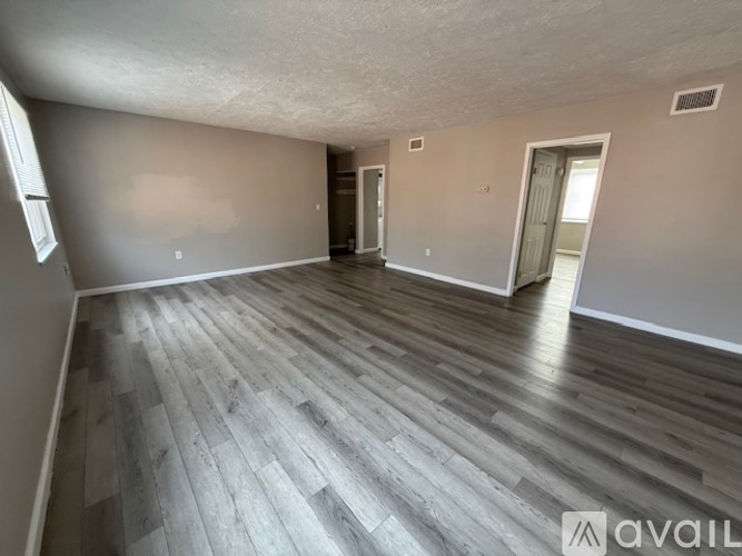 A spacious room with wooden flooring and two doors.
