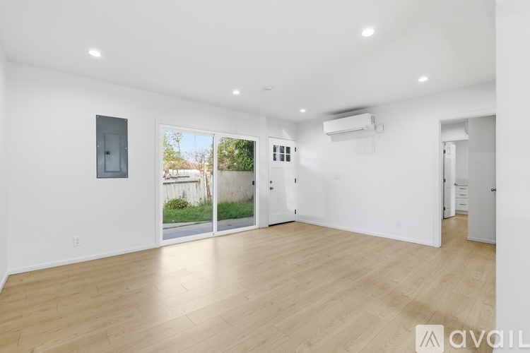A spacious room with wooden flooring and a large window.
