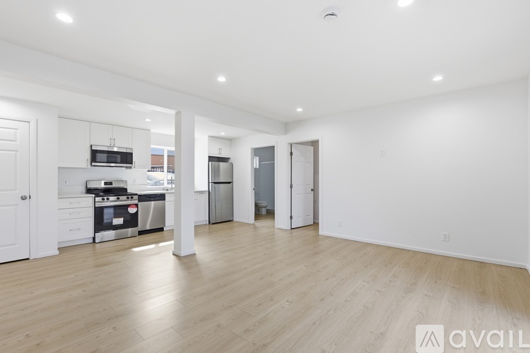 A spacious kitchen with white cabinets and a wooden floor.