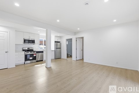 A spacious kitchen with white cabinets and a wooden floor.