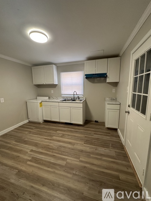 A kitchen with white cabinets and a wooden floor.