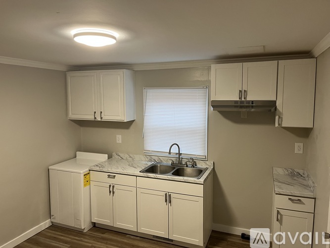 A kitchen with white cabinets and a sink under a window.