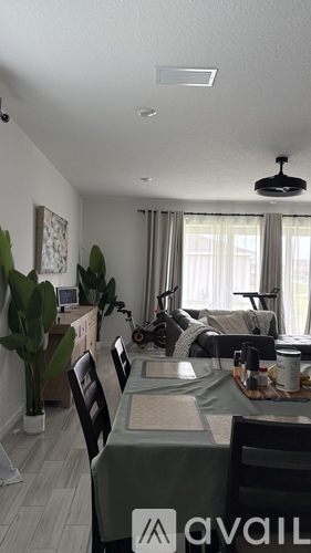 A dining room with a table set for four and a couch in the background.