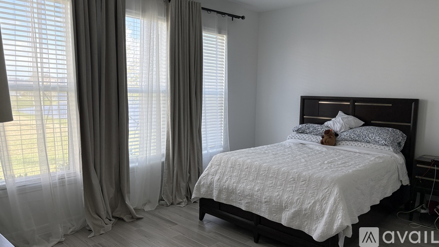 A bedroom with a large bed and a window with curtains.