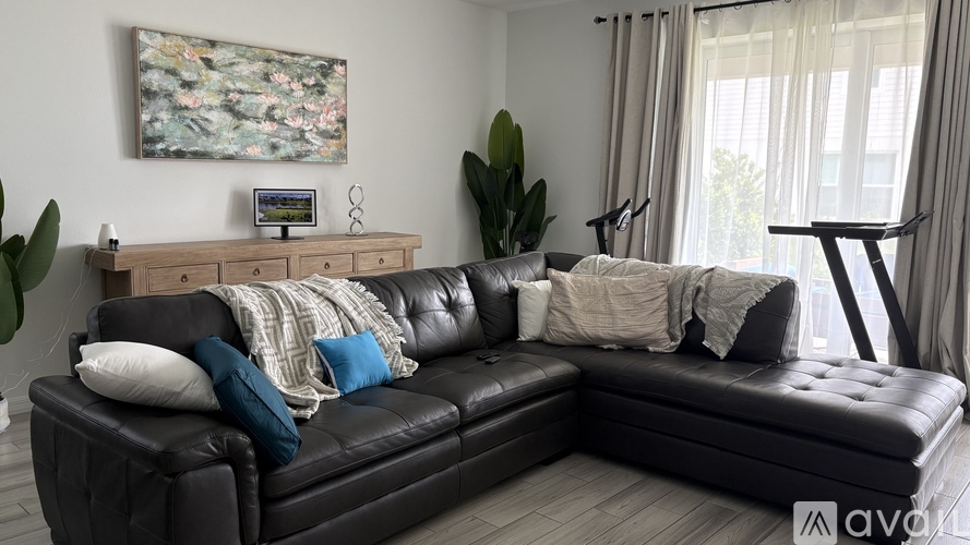 A black leather couch with a blanket on it in a living room.