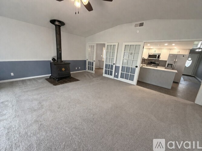 A living room with a wood stove and a kitchen in the background.
