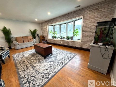 A living room with a brick wall and a large rug.