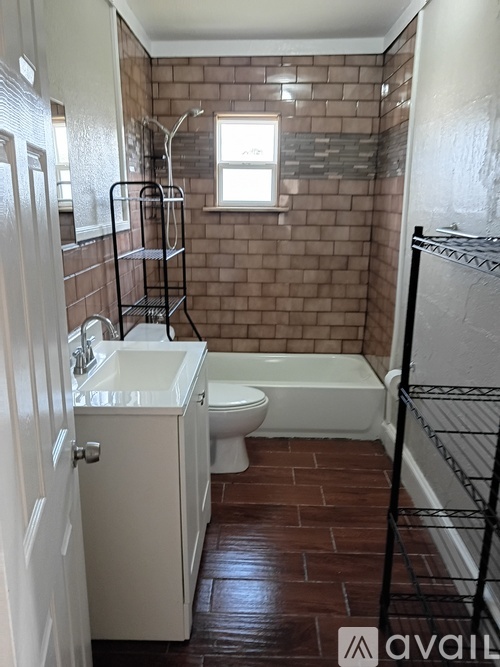 A bathroom with a brown tiled wall and a white sink and toilet.