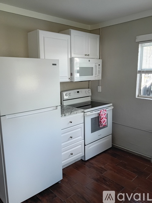 A kitchen with white appliances and wooden floors.