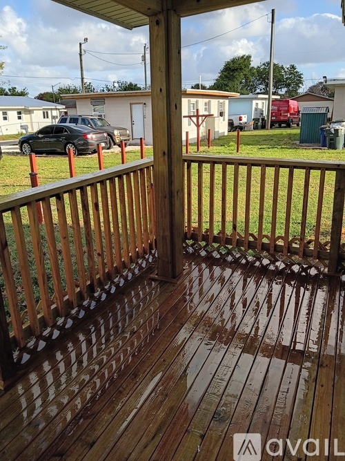 A wooden deck with a railing and a car parked in the background.