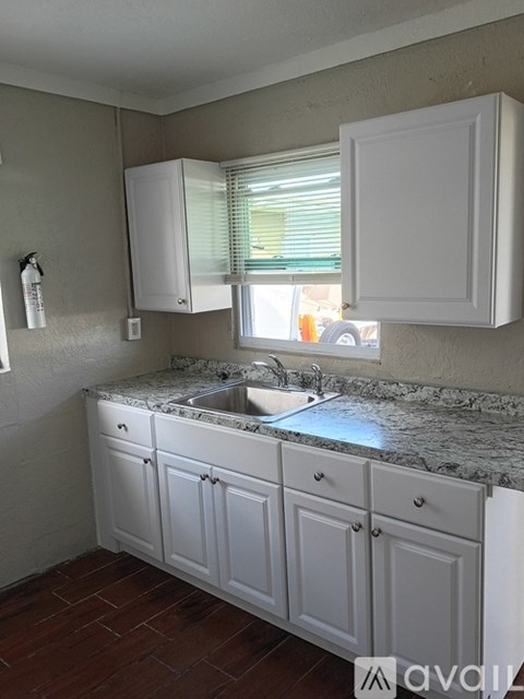 A kitchen with white cabinets and a marble countertop.