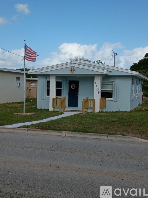 A small building with a flag on top and the number 1208 on the front door.