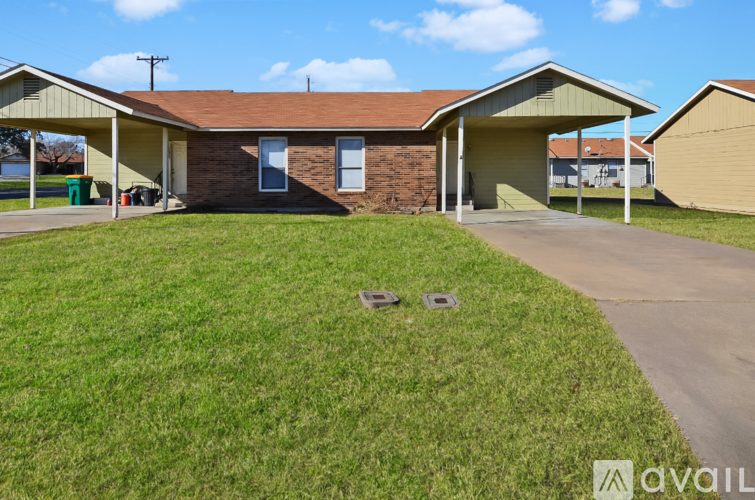 A house with a brown roof and a green lawn in front.