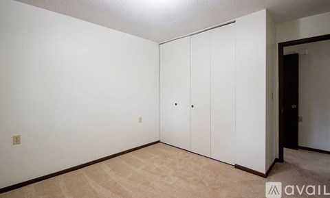 A room with white walls and a carpeted floor with a set of white cupboards.