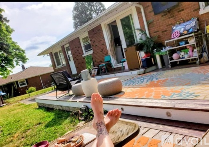 A person's feet are propped up on a chair on a patio with a house in the background.