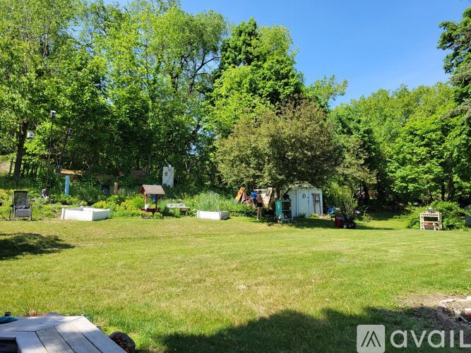 A grassy field with trees and a picnic table in the foreground.