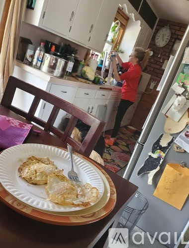 A woman in a red shirt is standing in a kitchen.