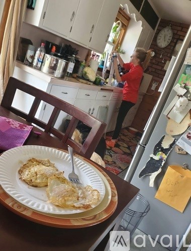 A woman in a red shirt is standing in a kitchen.