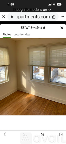 A room with wooden flooring and two windows.