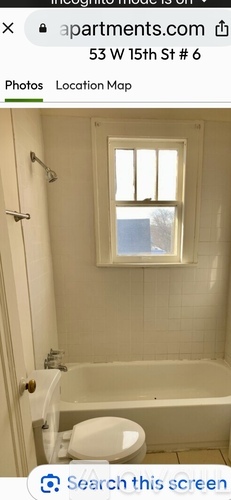 A white toilet is in a small bathroom with a window.