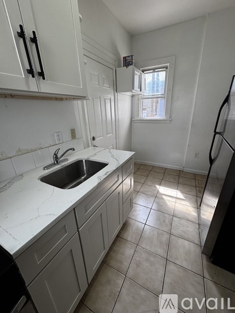 A kitchen with white cabinets and a marble countertop.